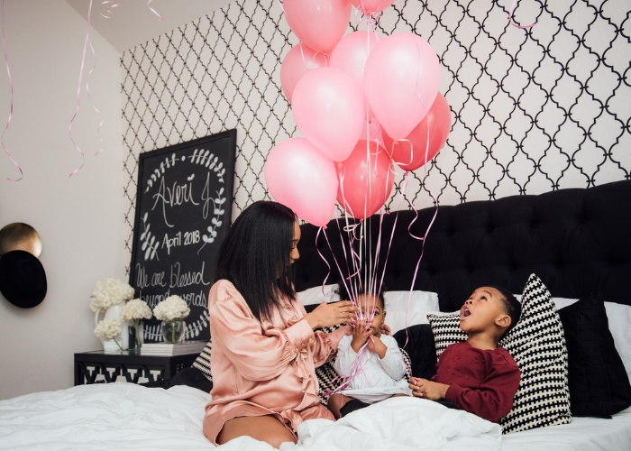 niños y mamá en la cama felices con unos globos 